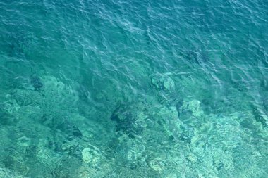 Gök mavisi su dokusu, kayalık tabanlı şeffaf deniz yüzeyi. Hava görüntüsü, doğal mavi arkaplan