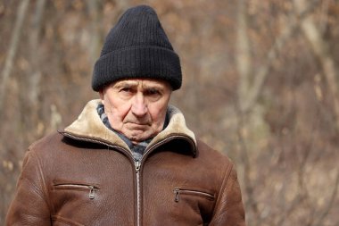 Sonbahar parkında duran sert yaşlı adamın portresi. Yaşlılık kavramı, köy hayatı.