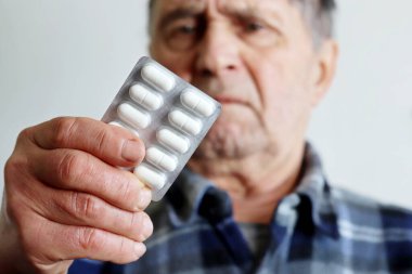 Su toplayan beyaz haplarla yaşlı bir adam, koronavirüs tedavisi ve önleme. Tıbbi reçete, soğuk algınlığı ve grip kavramı