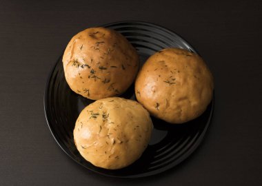 Ahşap bir masa üzerinde siyah bir plaka üzerinde üç rulo