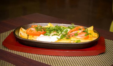 Patates ve domates ve yeşillik bir tavada bir tablo üzerinde sahanda yumurta