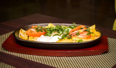 Patates ve domates ve yeşillik bir tavada bir tablo üzerinde sahanda yumurta