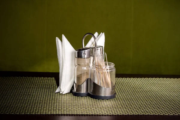 Pepper shaker, salt shaker and napkins on a stand on a table