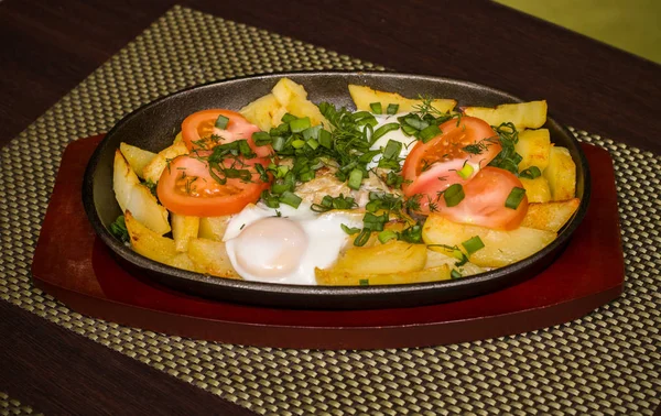 Patates ve domates ve yeşillik bir tavada bir tablo üzerinde sahanda yumurta