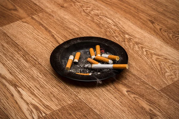 Aschenbecher mit rauchender Zigarette und Zigarettenkippen — Stockfoto