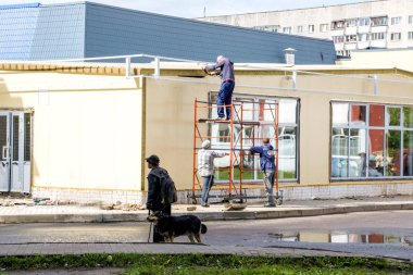 Novopolotsk, Belarus - 06 Temmuz 2018: Sarı bina ve iki inşaatçılar İnşaat