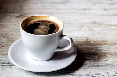 Bir fincan kahve ve bir ahşap beyaz masa üzerinde bir daire