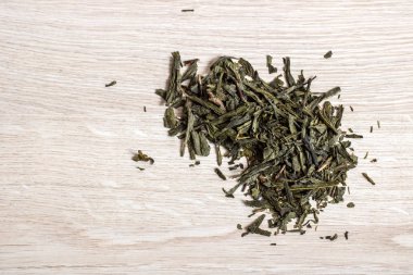 Ahşap bir masada kurumuş yeşil çay yaprakları.