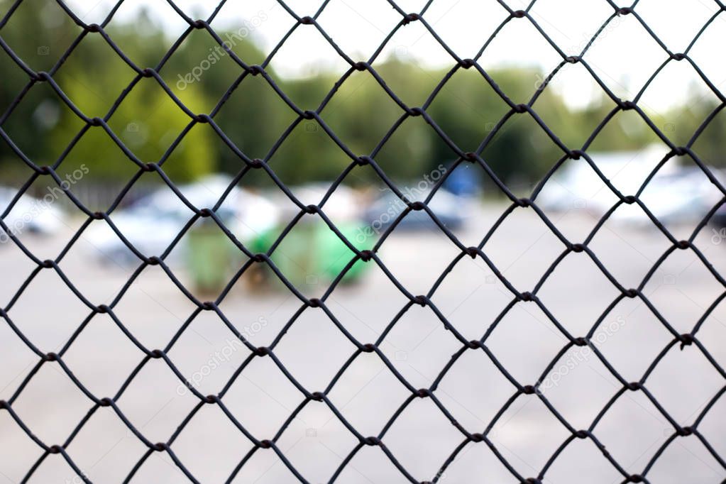 Black mesh fence, background for text, trees and car parking