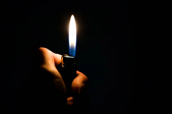 Una mano che tiene un accendino con sopra la scritta candela