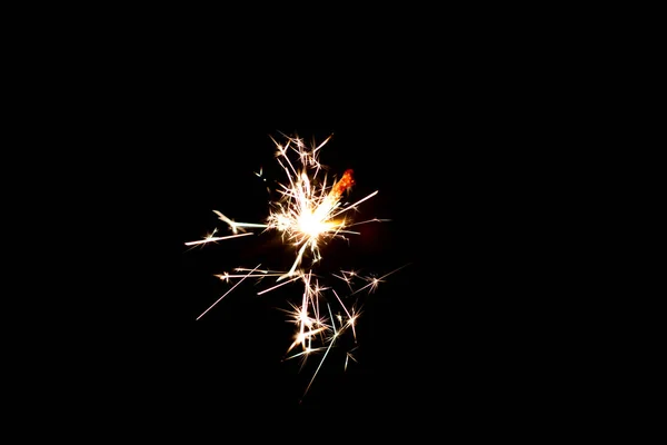 Yellow spark of sparkler on a black background, close up