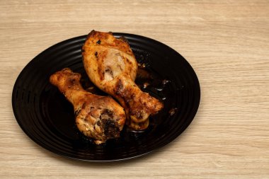 Ahşap bir masa üzerinde bir tabakta tavuk budu pişmiş