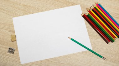 Kurşun kalem, silgi, kalemtıraş ve ahşap bir masa üzerinde bir kağıdın 