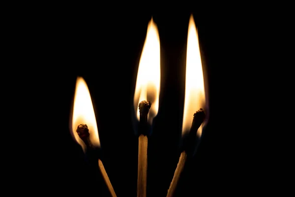 Tres cerillas ardientes en la oscuridad de cerca —  Fotos de Stock