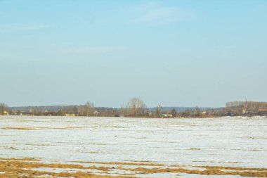 Kış güneşli manzara, alan orman ve evler, erken ilkbaharda kar erir