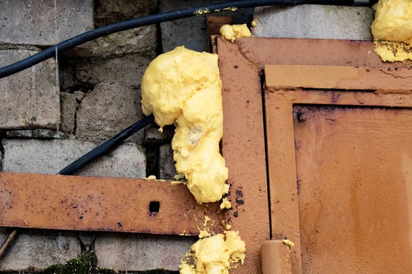 Canto de uma porta metálica amarela em uma parede de tijolo — Fotografia de Stock