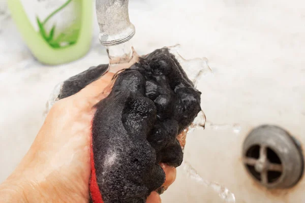 Black washcloth with foam in hand close up — Stock Photo, Image