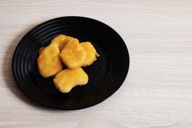Huş ağacı tablo üzerinde siyah bir tabakta tavuk nuggets