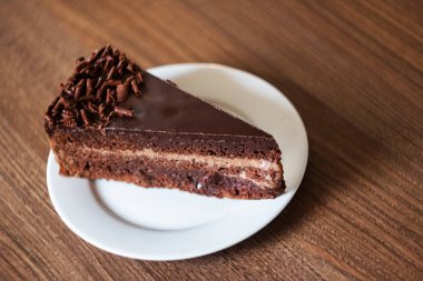 Ahşap bir masada beyaz bir tabak ta çikolatalı kek