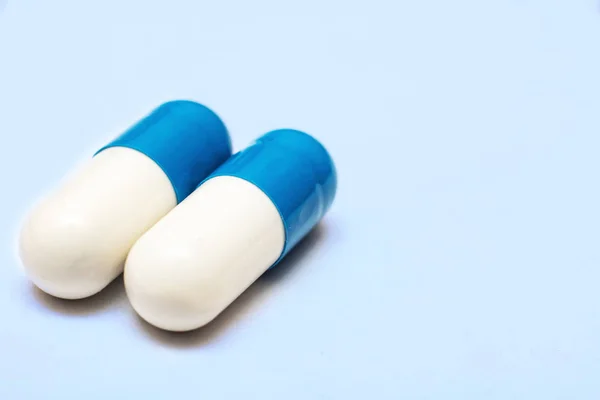 青い背景に2つの白い青い薬の錠剤がクローズアップ — ストック写真