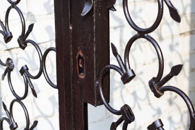 Bir tuğla duvar arka plan üzerinde yakın bir metal dövme çit üzerinde anahtar deliği