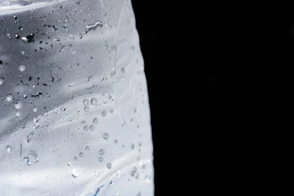 Bubbles in a cold water bottle on a black background close up
