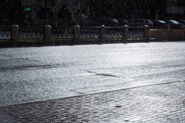 Şehir yolu arka planında yağmur damlaları ve güneş ışığı
