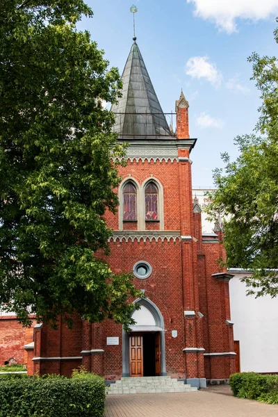Old red brick church among green trees in Polotsk