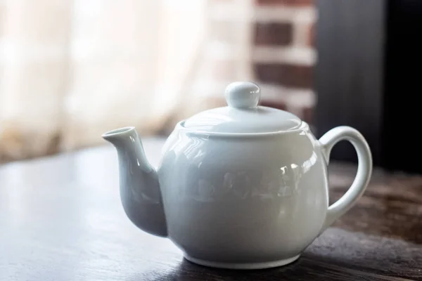 Bule branco com chá em uma mesa de madeira — Fotografia de Stock