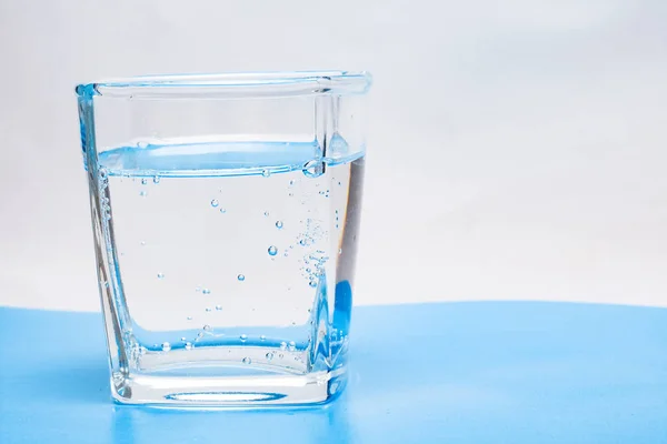 Glass cup with water with bubbles on a white background — Stock Photo, Image