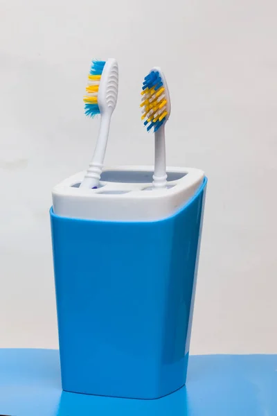 Two toothbrushes in a glass on a blue background — Stock Photo, Image