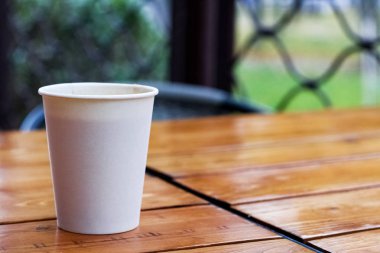 Tahta bir masada beyaz kağıt bardak ve kahve.