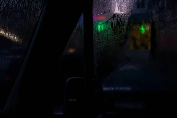 Boczne okno samochodu w nocy z kroplami deszczu — Zdjęcie stockowe