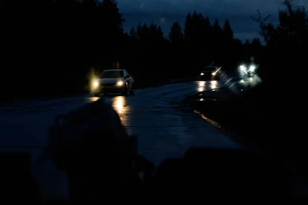 Ventana delantera del coche con gotas de lluvia y carretera con coches por la noche —  Fotos de Stock
