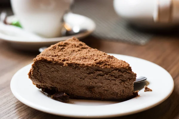 Piece of chocolate cake on white plate on background of cup of tea — Stock Photo, Image