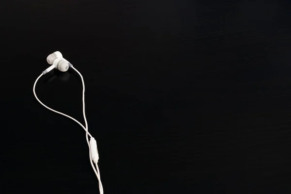 Auriculares blancos en una mesa de madera negra — Foto de Stock