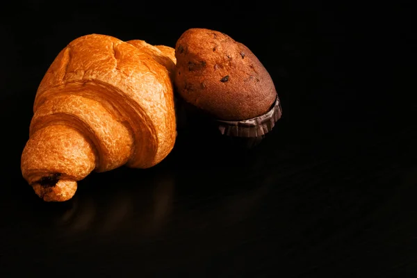 Ruddy croissant dengan coklat dan cupcake di atas meja kayu hitam — Stok Foto