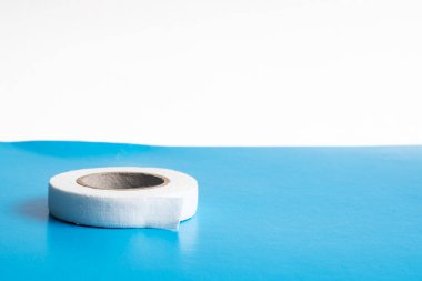 Mavi arka planda tıbbi yapıştırıcı rulosu.