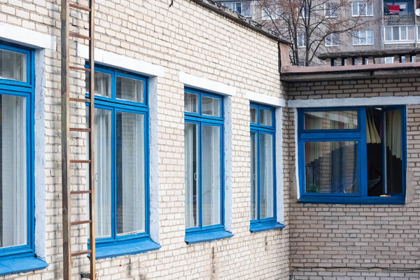 Blue windows of a brick building and a staircase to the roof