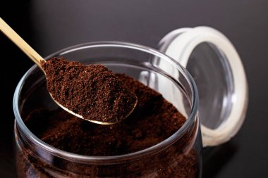 Cam kavanozda öğütülmüş kahve ve masada kaşık.