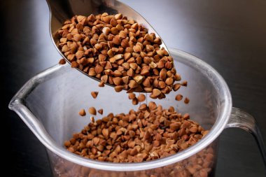 Karabuğday siyah arka planda kaşıkta inliyor.