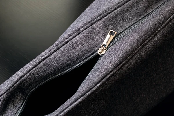 Open gray travel bag on a wooden background close up