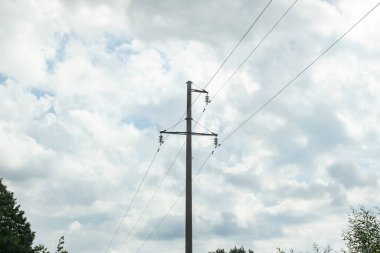 Karanlık bulutlu bir gökyüzüne karşı kablolarla kutup