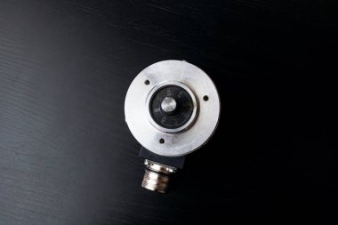 Siyah ahşap bir masa üzerinde metal kodlayıcı, üst görünüm