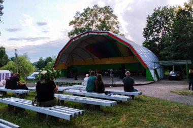 BELARUS, POSTAVY - 21 AĞUSTOS 2020: Açık hava sahnesinin önündeki banklarda çok az insan