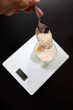Elektronik terazide pirinçli cam ve kaşık kapat.
