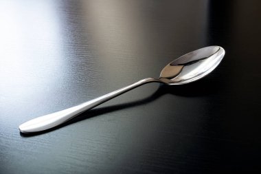 Siyah ahşap masada metal kaşık. Yaklaş.