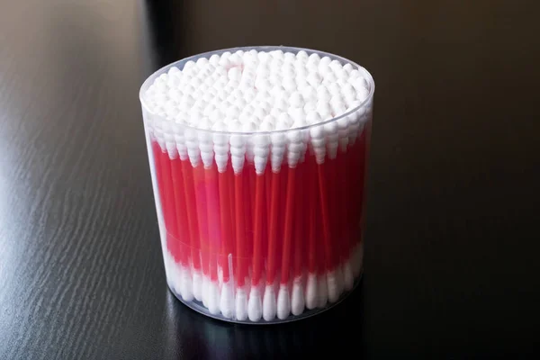 Botões de algodão vermelho no frasco na mesa de madeira — Fotografia de Stock