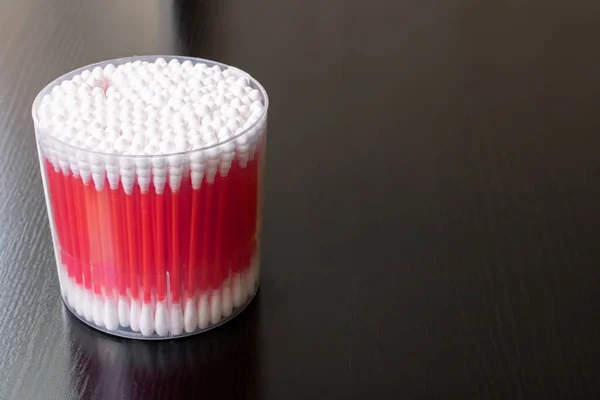 Botões de algodão vermelho no frasco na mesa de madeira — Fotografia de Stock