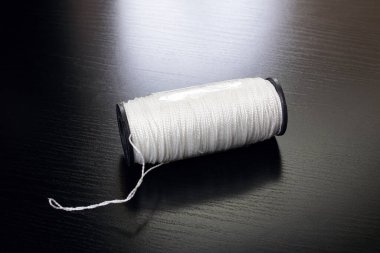 Siyah ahşap bir masada beyaz iplik makarası